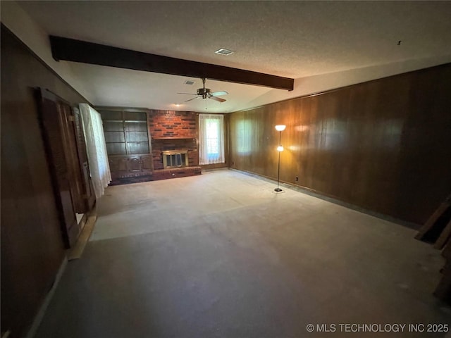 unfurnished living room with wooden walls, concrete flooring, a brick fireplace, a ceiling fan, and vaulted ceiling with beams