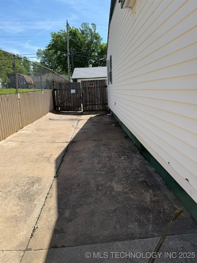 view of side of home featuring fence and concrete driveway