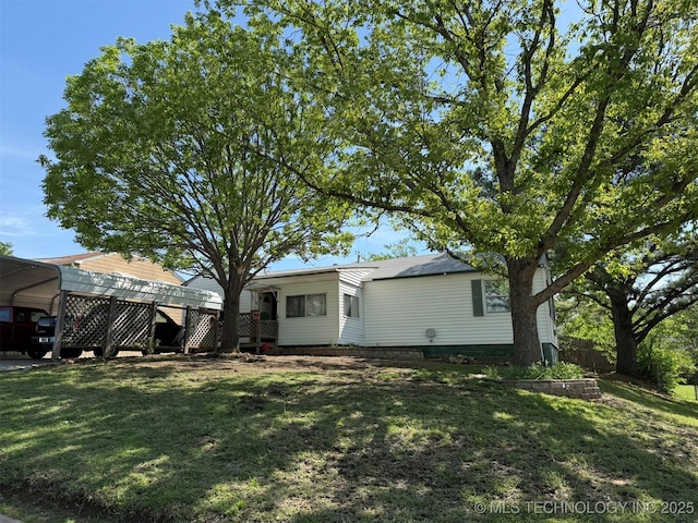 rear view of house with a detached carport and a yard