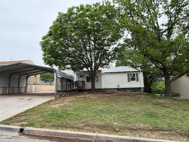 view of front of house with fence, driveway, a front yard, and a carport