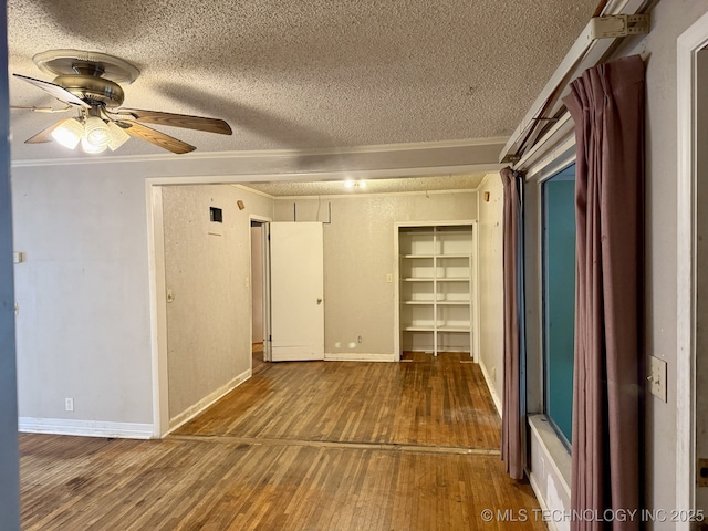 empty room featuring wood-type flooring, a textured ceiling, crown molding, and ceiling fan
