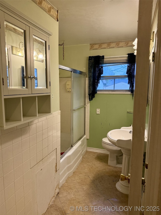 bathroom featuring shower / bath combination with glass door, tile patterned floors, and toilet