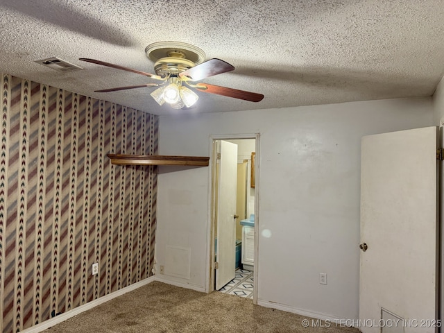 carpeted empty room featuring visible vents, a ceiling fan, and a textured ceiling