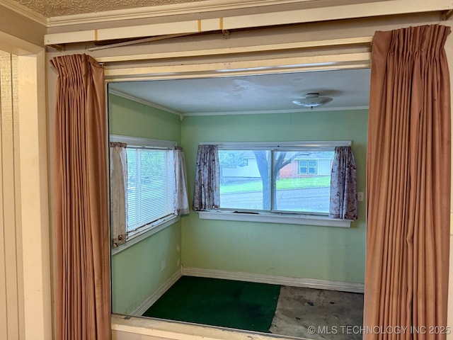 spare room featuring crown molding and baseboards