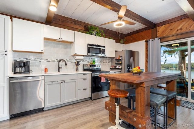 24591 S 613th Rd, Grove, OK 74344 - kitchen featuring light wood-style floors, light countertops, stainless steel appliances, backsplash, and beamed ceiling