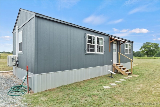 view of side of home with a lawn, ac unit, and entry steps