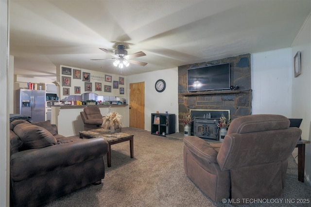 living area with carpet floors, a ceiling fan, and a wood stove