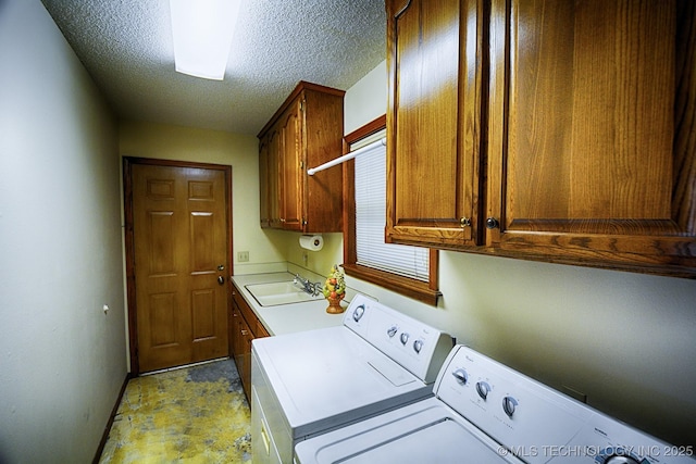 washroom featuring baseboards, washer and clothes dryer, a textured ceiling, a sink, and cabinet space