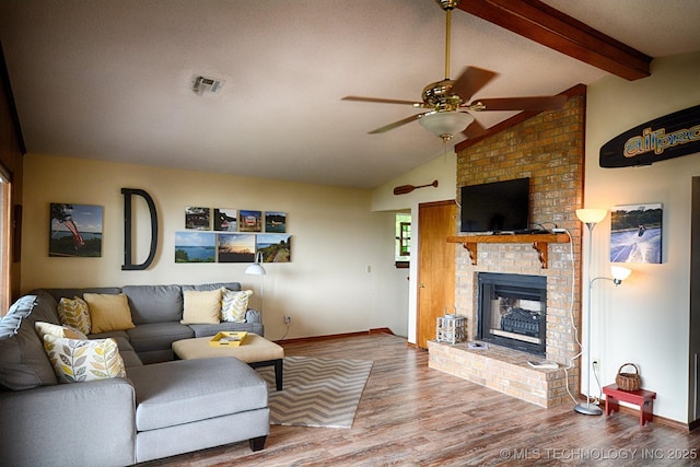 living room with ceiling fan, visible vents, a fireplace, wood finished floors, and baseboards