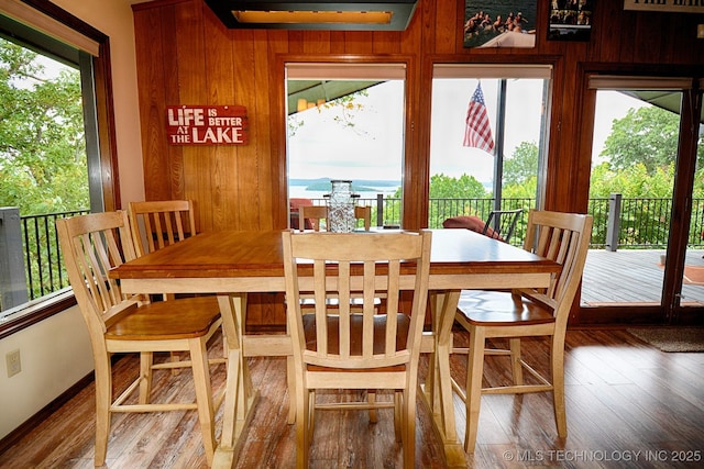 dining area with wood walls, wood finished floors, and a wealth of natural light