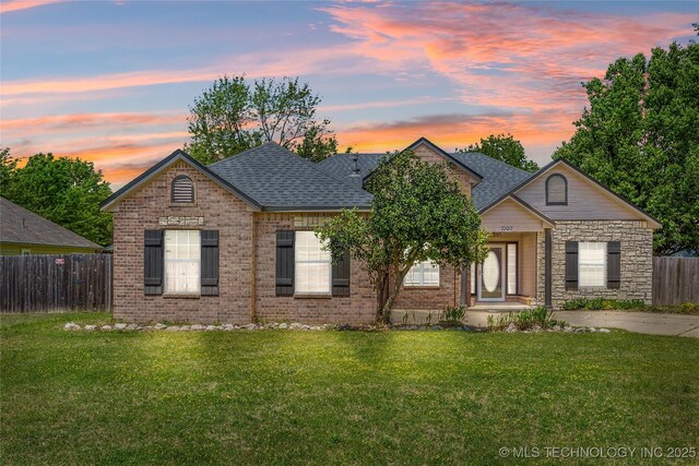 1007 W Beech St, Skiatook, OK 74070 - view of front of house with fence, a shingled roof, a front lawn, and brick siding