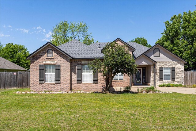 1007 W Beech St, Skiatook, OK 74070 - view of front of house featuring fence, a shingled roof, brick siding, and a front yard