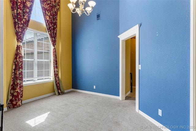 spare room with carpet flooring, baseboards, an inviting chandelier, and visible vents