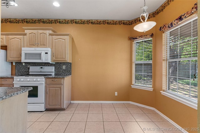 kitchen with light brown cabinetry, white appliances, dark stone counters, light tile patterned floors, and backsplash