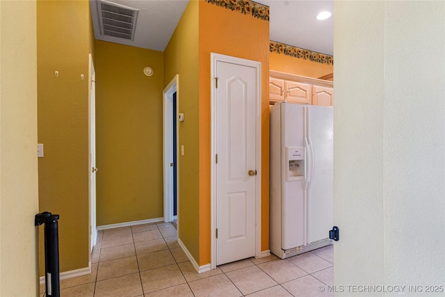 corridor featuring baseboards, visible vents, and light tile patterned floors