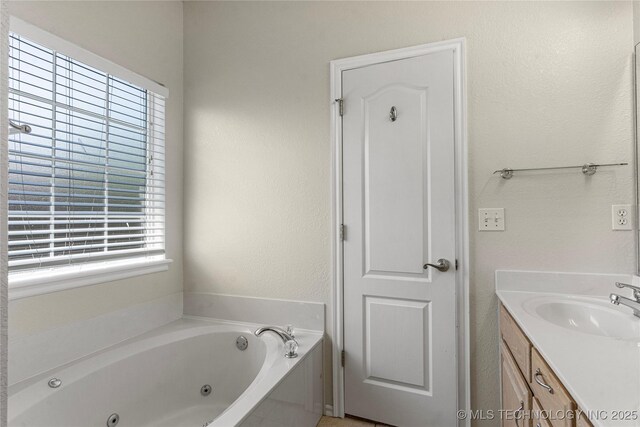 1007 W Beech St, Skiatook, OK 74070 - full bath with a whirlpool tub, a textured wall, a healthy amount of sunlight, and vanity