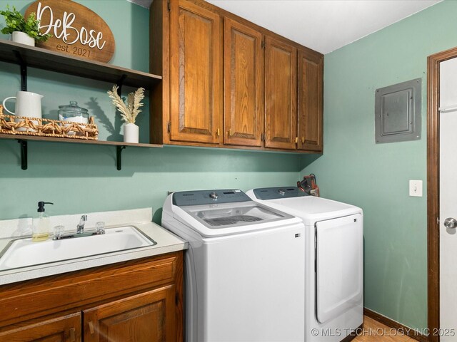 laundry room with a sink, cabinet space, independent washer and dryer, and electric panel