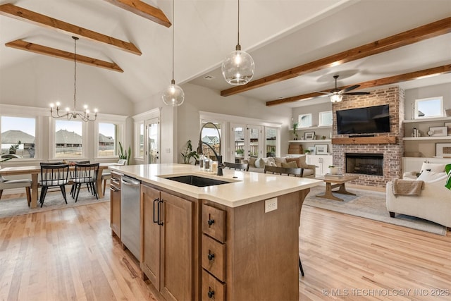 kitchen featuring light wood-style floors, an island with sink, a sink, and a fireplace