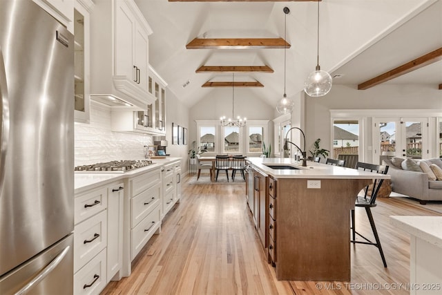 kitchen featuring a sink, stainless steel appliances, beam ceiling, and a wealth of natural light