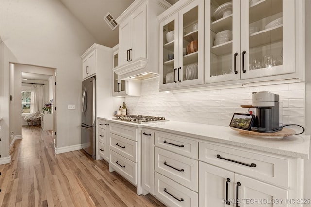 kitchen with visible vents, decorative backsplash, white cabinetry, vaulted ceiling, and stainless steel appliances