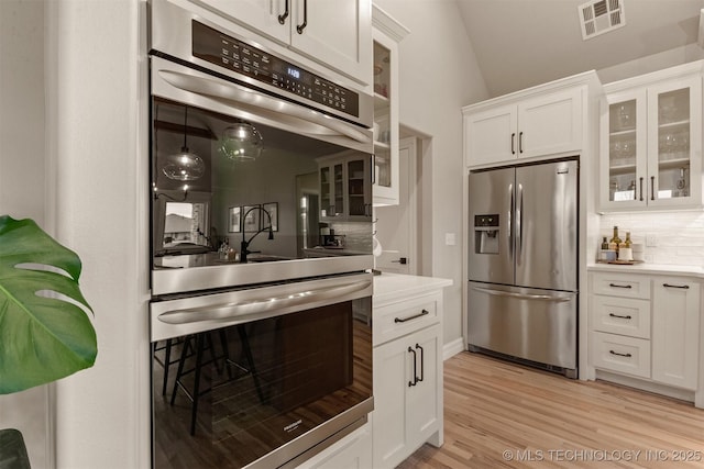 kitchen featuring visible vents, light countertops, light wood-style floors, stainless steel appliances, and white cabinetry