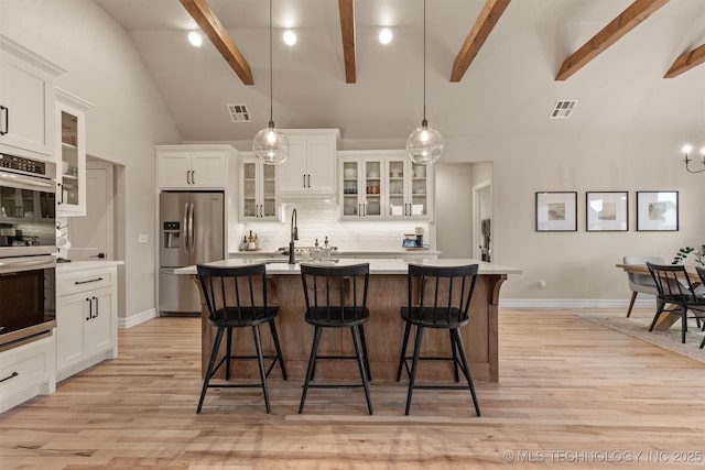 kitchen with appliances with stainless steel finishes, light wood-style flooring, visible vents, and tasteful backsplash