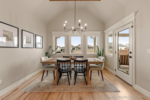 dining space with baseboards, a notable chandelier, light wood finished floors, and high vaulted ceiling