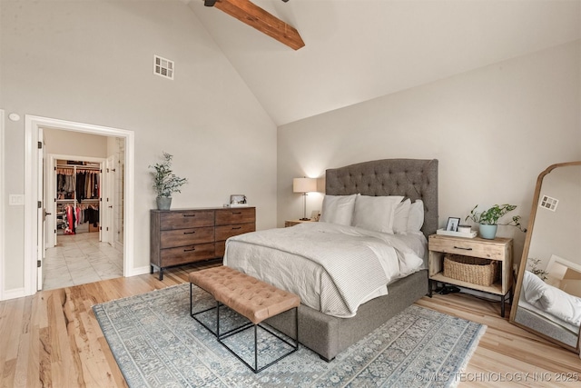 bedroom featuring visible vents, wood finished floors, high vaulted ceiling, baseboards, and a spacious closet