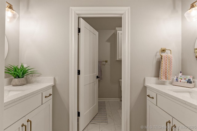 bathroom with a sink, marble finish floor, two vanities, and toilet