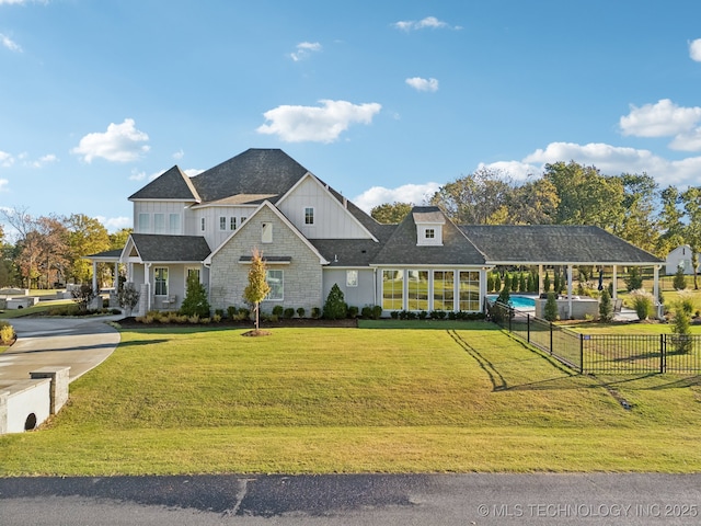 view of front of house featuring board and batten siding, fence, and a front yard