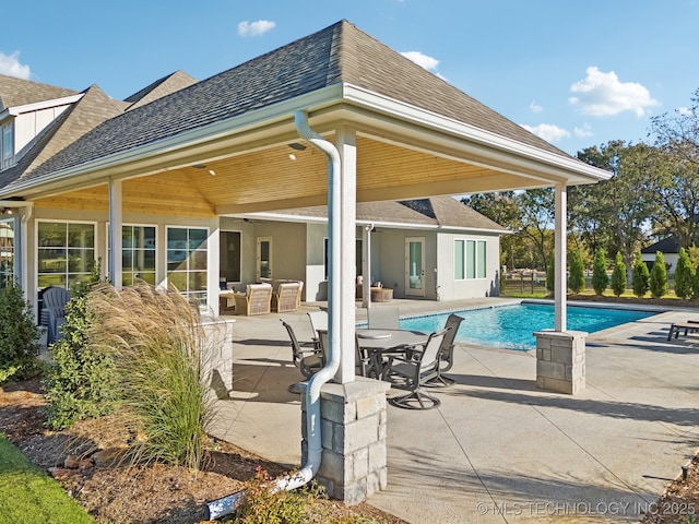 rear view of property featuring a shingled roof, an outdoor living space, and a patio area