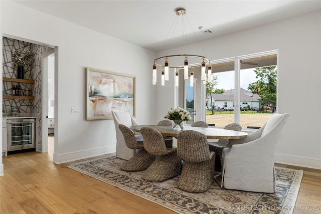 dining area with visible vents, baseboards, light wood finished floors, beverage cooler, and a notable chandelier