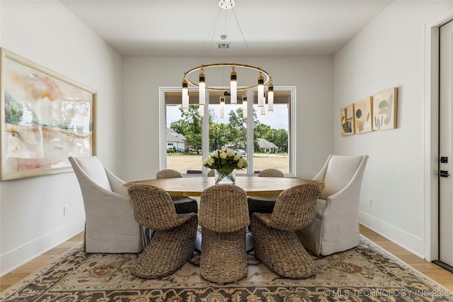 dining space with baseboards, visible vents, wood finished floors, and a chandelier