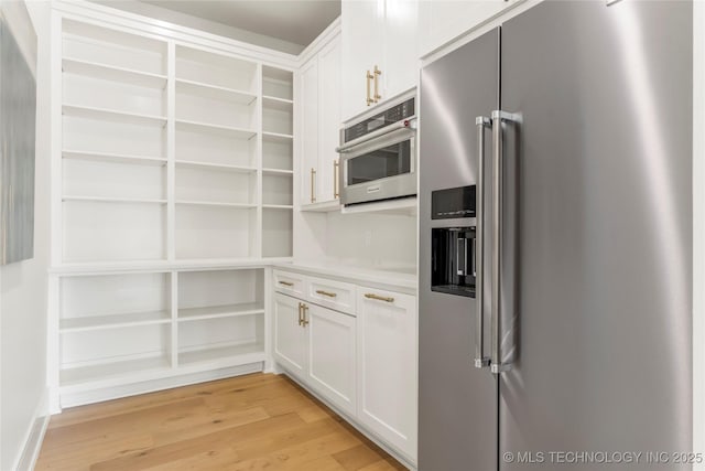 kitchen featuring appliances with stainless steel finishes, open shelves, light countertops, white cabinets, and light wood-style flooring