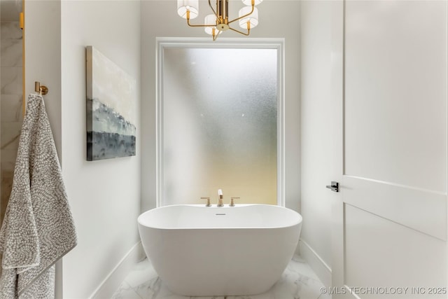 bathroom with baseboards, a soaking tub, a notable chandelier, and marble finish floor