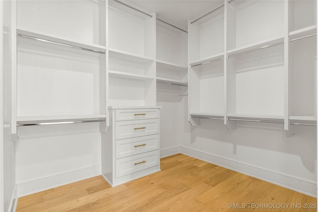 walk in closet with light wood-style floors