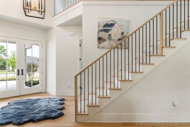 entrance foyer with french doors, baseboards, wood finished floors, a towering ceiling, and stairway