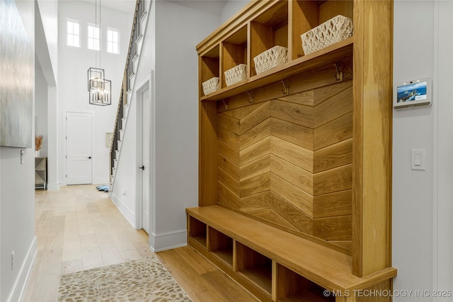 mudroom with baseboards, light wood finished floors, and a chandelier