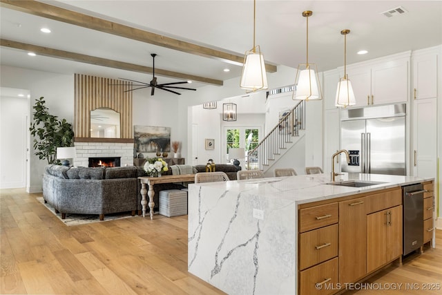 kitchen with ceiling fan, visible vents, a sink, open floor plan, and stainless steel appliances