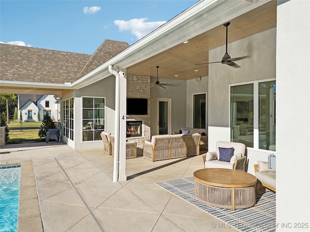 view of patio with a ceiling fan, an outdoor living space with a fireplace, and an outdoor pool