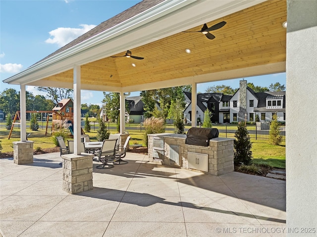 view of patio / terrace with fence, a residential view, an outdoor kitchen, ceiling fan, and outdoor dining area