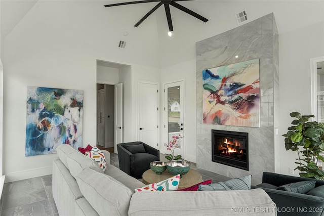 living room featuring a premium fireplace, a ceiling fan, visible vents, and high vaulted ceiling