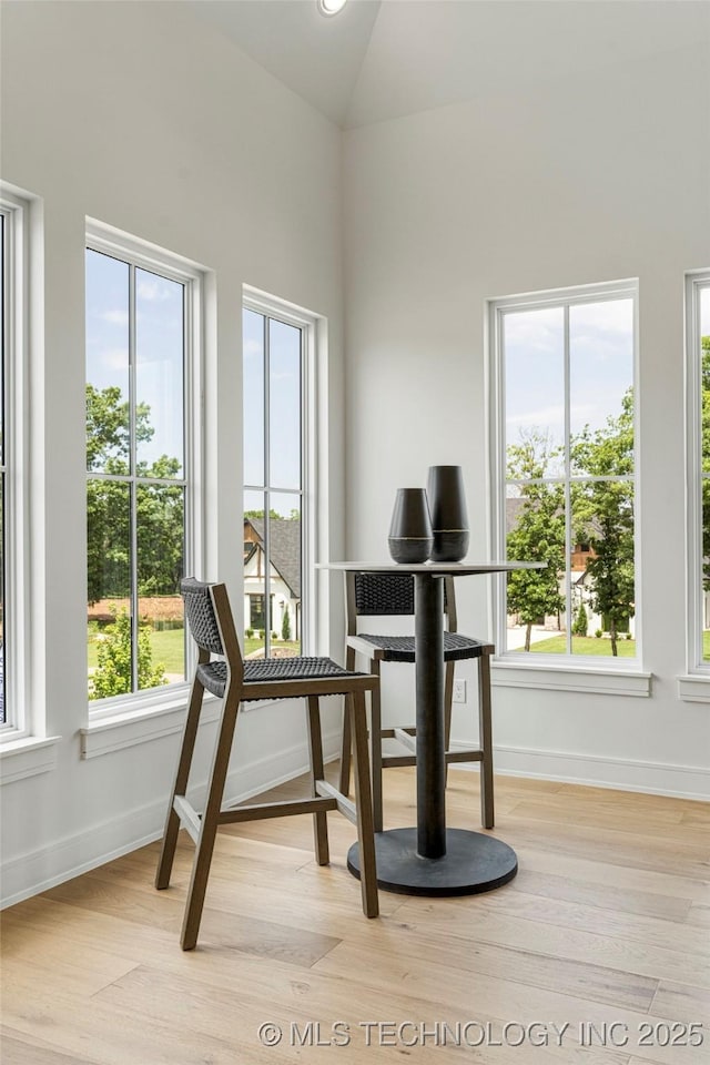 sitting room with baseboards, lofted ceiling, and light wood finished floors