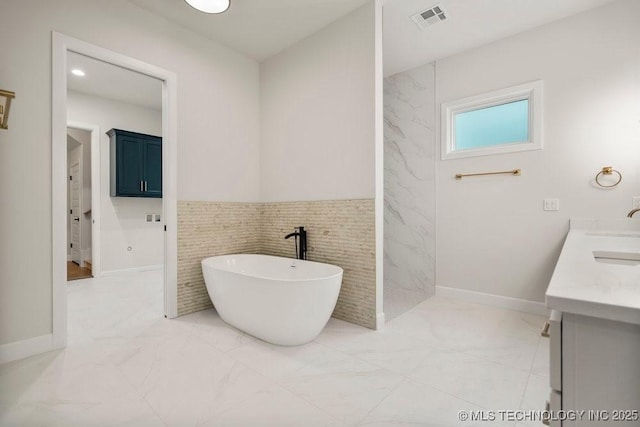 full bathroom featuring a freestanding tub, wainscoting, marble finish floor, and visible vents