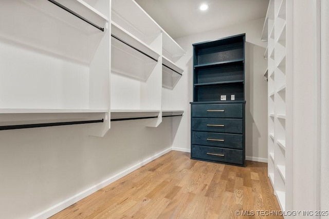 walk in closet with light wood-style flooring