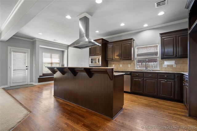 9502 S 73rd E Ave, Tulsa, OK 74133 - kitchen featuring island range hood, a kitchen bar, dark wood-type flooring, tasteful backsplash, and appliances with stainless steel finishes