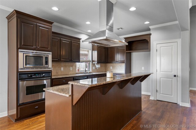 9502 S 73rd E Ave, Tulsa, OK 74133 - kitchen with island exhaust hood, ornamental molding, baseboards, and appliances with stainless steel finishes