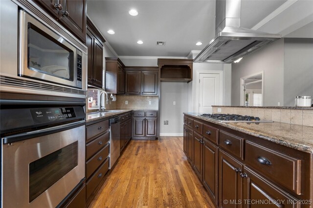 9502 S 73rd E Ave, Tulsa, OK 74133 - kitchen with island exhaust hood, appliances with stainless steel finishes, tasteful backsplash, a sink, and light stone counters