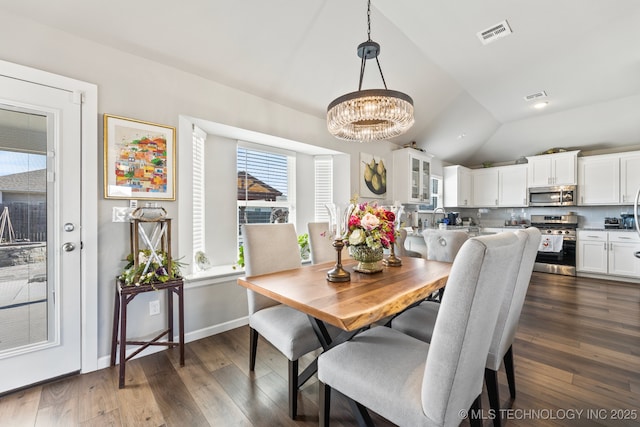 dining space with visible vents, a chandelier, vaulted ceiling, and dark wood-style floors