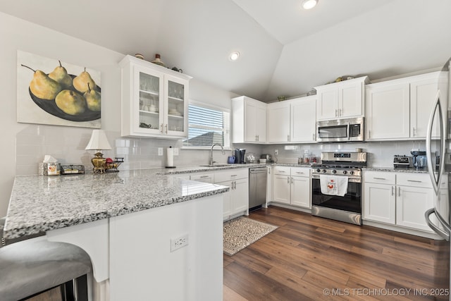 kitchen with a sink, white cabinets, a peninsula, glass insert cabinets, and stainless steel appliances